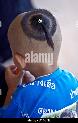 Tradizionale testa rasata e top knot acconciatura su un bambino thailandese. Thailandia SUDEST ASIATICO Foto Stock