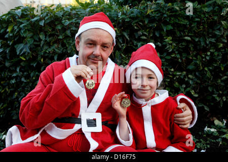 Domenica 9 dicembre 2012, Santa Dash carità Fun Run, George Square, Glasgow. Andrew Fullwood, di 45 anni, e sua figlia Caitlin Fullwood, 10 anni, mostra le loro medaglie dopo la finitura della Santa Dash carità fun run che è stato sponsorizzato dal Daily Record Alamy Live News Foto Stock