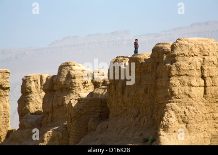 Un ragazzo si erge sulla cima delle rovine di antiche città Gaochang vicino a Turfan lungo la Silkroad, Uyghur Regione autonoma, Cina Foto Stock