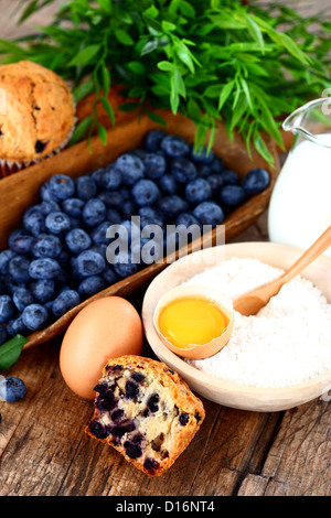 Muffin con mirtillo, l'uovo, la farina e il latte sul tavolo di legno Foto Stock