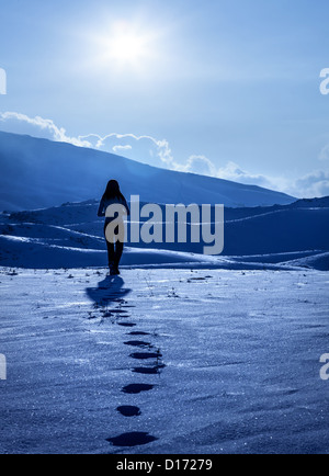 Immagine della lonely silhouette di donna in montagne invernali, Impronte sulla neve, godendo di inverno la natura vista,una ragazza camminare Foto Stock