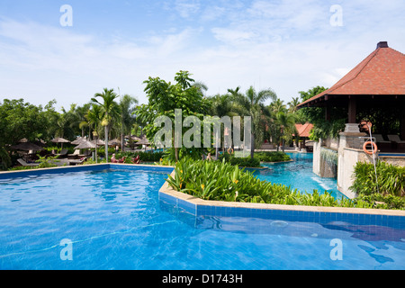 Piscina nel giardino tropicale con fiori e alberi a bordo piscina Foto Stock