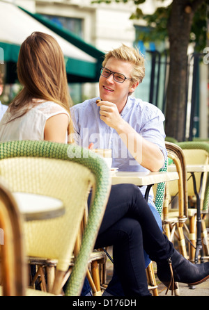 Carino guy ascoltando la sua fidanzata in un soleggiato aperto cafe Foto Stock