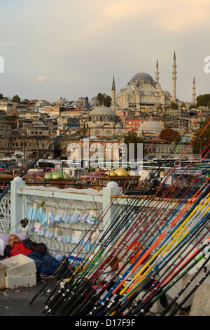 Uomo dorme sul Ponte di Galata con canne da pesca su Golden Horn con la Moschea di Suleymaniye Istanbul Turchia Foto Stock