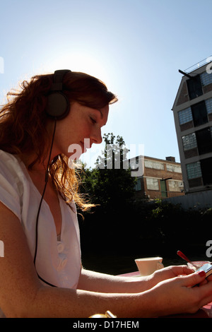 La donna le cuffie in un caffè Foto Stock