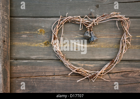 Vecchio rustico fatte a mano a forma di cuore ad ghirlanda, appeso a una parete in legno esterno Foto Stock