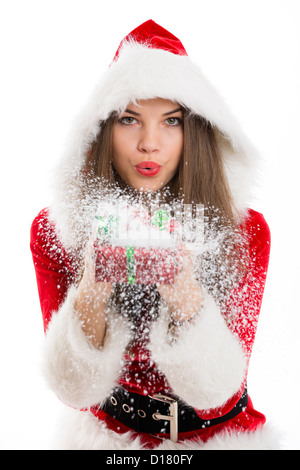 Santa bella ragazza lavori di soffiaggio della neve fuori il regalo di Natale scatola in mano. Foto Stock