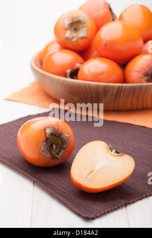 Fresco tropicale esotico mature succosa frutta arancione persimmon Diospyros servita nel piatto di legno sul tavolo Foto Stock