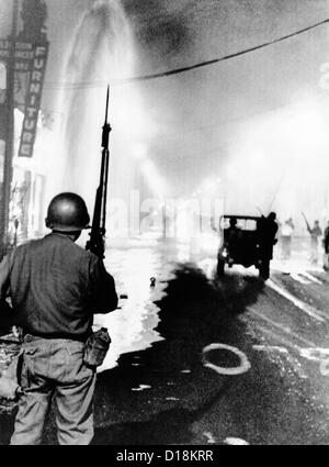 La Guardia Nazionale in watt durante la gara 1965 sommossa. I detriti cucciolate le strade e un geyser da broken idrante di fuoco spray a Foto Stock