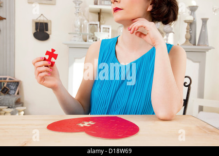 Donna facendo a forma di cuore ad puzzle pezzo di contenimento Foto Stock