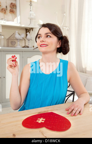 Donna facendo a forma di cuore ad puzzle pezzo di contenimento Foto Stock