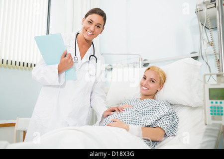 Ostetrico femmina parlando a un sorridente donna in stato di gravidanza Foto Stock