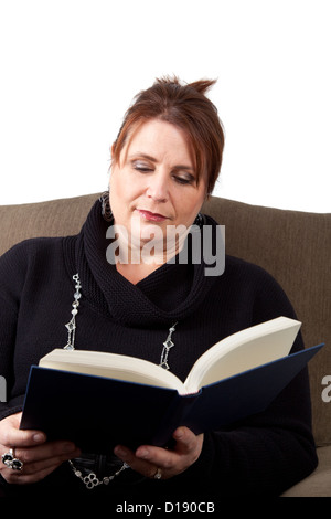 Un bruscamente vestito donna di mezza età si rilassa in una sedia e legge. Foto Stock