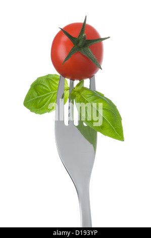 Cherry pomodoro e basilico foglie su una forcella contro uno sfondo bianco Foto Stock