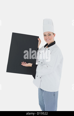 Lo chef femmina in uniforme visualizzando billboard nero Foto Stock