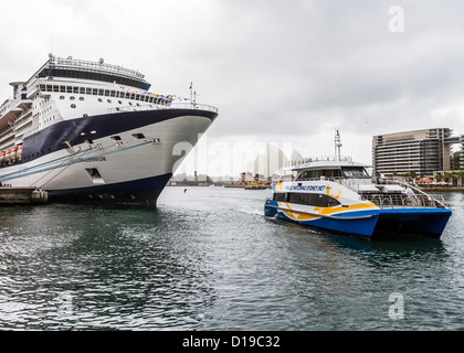 Catamarano traghetto passa Celebrity Millenium nave da crociera ormeggiata al terminal delle crociere nel porto di Sydney. Foto Stock