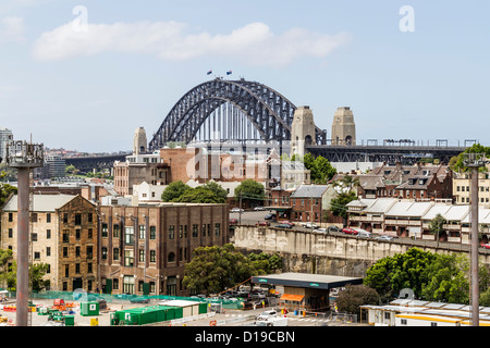 Le rocce di Sydney con il nuovo terminal per navi da crociera in costruzione in primo piano e il Sydney Harbour Bridge in background. Foto Stock