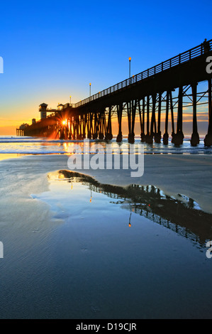 Oceanside pier e riflessioni, catturata su un estremamente bassa marea di sera. Foto Stock