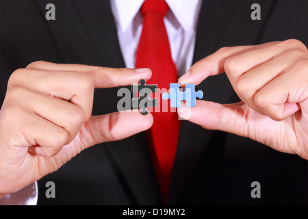 Imprenditore azienda jigsaw collegamento con due mani Foto Stock