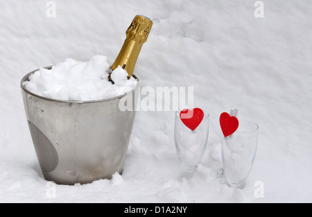 Due bicchieri con cuori rossi e champagne raffreddata nella neve Foto Stock