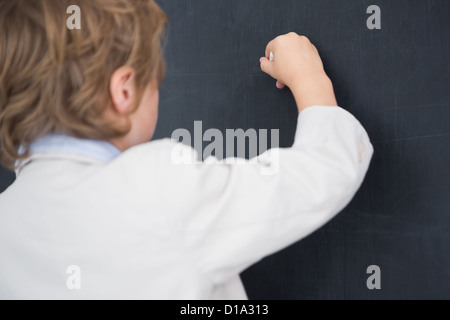 Ragazzo vestito come insegnante e scrive sulla lavagna nera Foto Stock