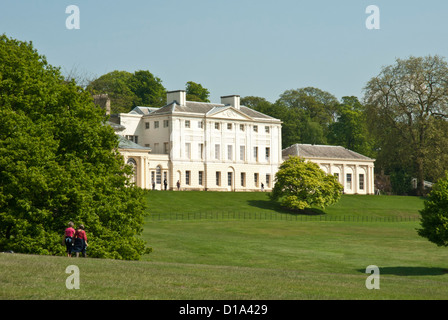 Kenwood House, Londra UK adagiato tra alberi maturi e parco, cielo blu giornata soleggiata, la gente a piedi di distanza. Foto Stock