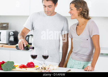 Il marito versando il vino rosso in cucina Foto Stock