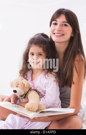 Madre e figlia insieme di lettura con Teddy bear Foto Stock
