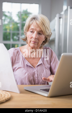 Focalizzato donna matura usando il suo computer portatile Foto Stock