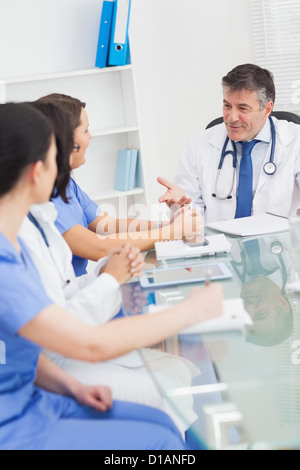 Incontro tra un medico e tre infermieri sorridente Foto Stock