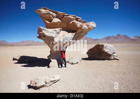 Donna che pongono sotto Arbol de Piedra (pietra albero) in Altiplano, dipartimento di Potosi, Bolivia Foto Stock