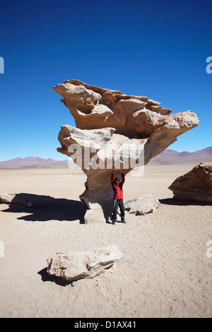 Donna che pongono sotto Arbol de Piedra (pietra albero) in Altiplano, dipartimento di Potosi, Bolivia Foto Stock
