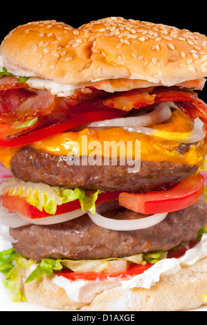 Doppia gigante hamburger con le fette di pomodoro, formaggio, crema di formaggio, pancetta, uova, la lattuga e la cipolla in un pane bianco bun Foto Stock