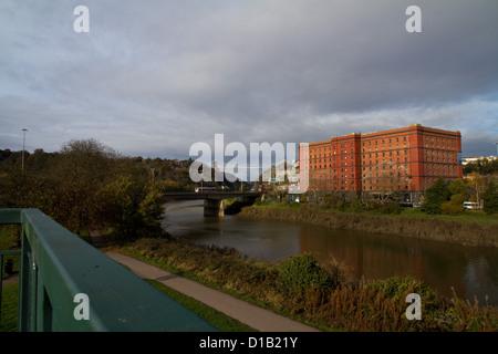 Una vista di un Red Brick Warehouse sul fiume Avon a Bristol, con il Clifton Suspension Bridge a distanza Foto Stock