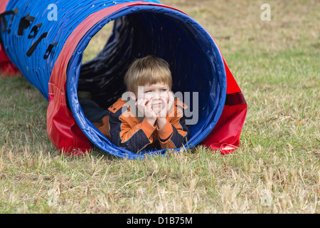 Ragazzo giovane giacente in un tunnel di agilità Foto Stock