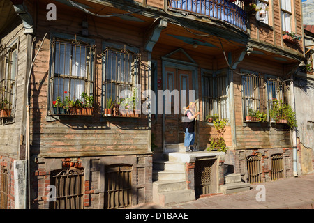 Donna in piedi presso la porta di uno storico Ottomano casa in legno in Kadirga Fatih Istanbul Turchia Foto Stock