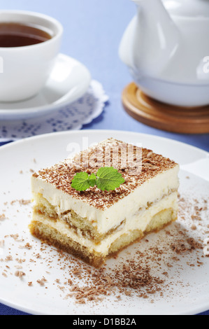 Il tiramisù - Classico dolce con il caffè sulla piastra bianca. Guarnite con foglie di menta. Foto Stock