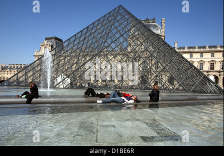 Parigi, Francia, persone crogiolarsi nella parte anteriore della piramide di vetro del Louvre Foto Stock