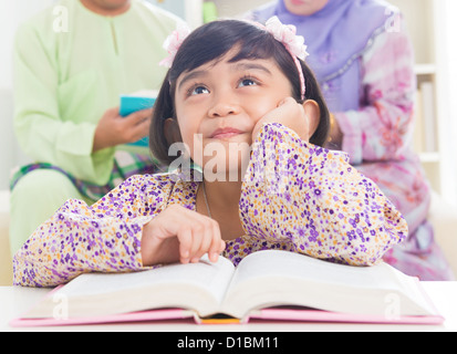 Sud-est asiatico famiglia libro di lettura a casa. Famiglia musulmana stile di vita vivente. Foto Stock