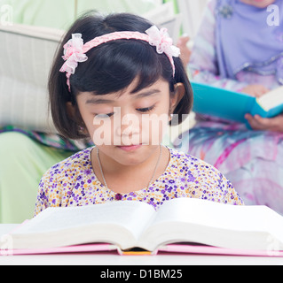 Famiglia musulmana stile di vita vivente. Sud-est asiatico di lettura della famiglia libro. Foto Stock