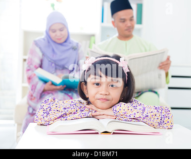 Sud-est asiatico lettura della ragazza a casa. Famiglia musulmana stile di vita vivente Foto Stock