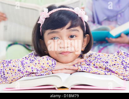 Ragazzina musulmana libro di lettura a casa. Sud-est asiatico vivere in famiglia lifestyle Foto Stock