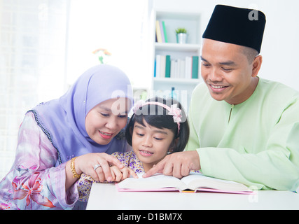Famiglia musulmana libro di lettura a casa. Sud-est asiatico vivere in famiglia lifestyle Foto Stock