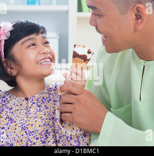 Carino Southeast Asian girl alimentando il gelato al padre. Malay musulmana lo stile di vita di famiglia Foto Stock