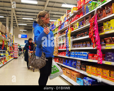 Blu Donna rivestita di shopping in superstore, piena di ripiani appena prima di Natale Foto Stock