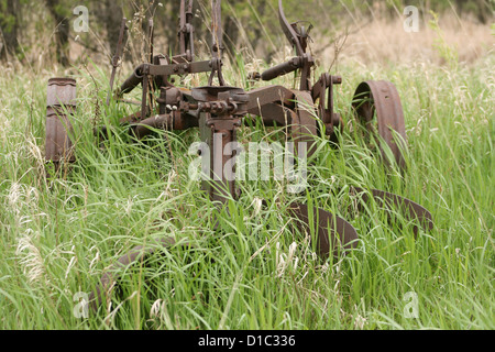 Un antico aratro ricoperta da erba in un campo di agricoltori in primavera a Winnipeg, Manitoba, Canada Foto Stock