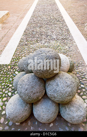 Antica pietra palla di cannone che dava sul cortile del Castello Estense di Ferrara, Italia Foto Stock