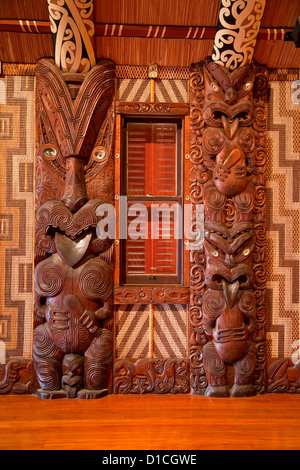 Scolpiti tradizionale Maori figura, denominata Poupou, sostenere il tetto di travi a vista del meeting house, Waitangi Treaty Grounds. Foto Stock