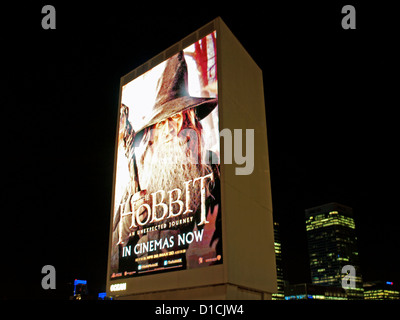 Vista di un cartellone pubblicità 'The Hobbit' durante la notte da Blackwall DLR station mostra Canary Wharf grattacieli in background Foto Stock