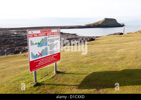 Segnaletica di pericolo attenzione di fast correnti di marea attraverso causeway, Worm Testa, Gower, Wales, Regno Unito Foto Stock